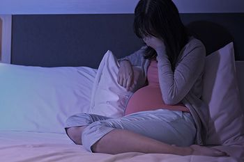 Deprimierte Schwangere sitzt auf dem Bett