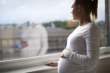 Nachdenkliche Schwangere blickt aus dem Fenster