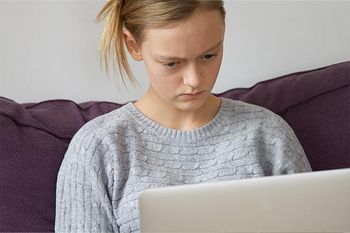 Jugendliche blickt kritisch auf Computermonitor