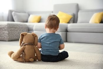 Autistisches Kleinkind sitzt neben seinem Kuschelhasen