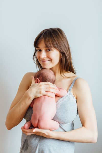 Junge Mutter hält nacktes Neugeborenes