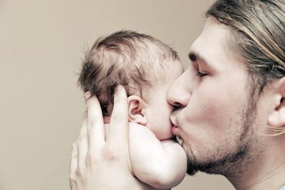 Porträt: Junger Vater küsst Säugling