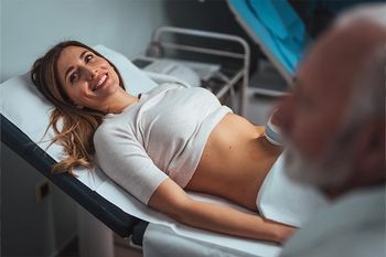 Frühschwangerschaft: Glückliche junge Frau bei Ultraschalluntersuchung