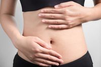 Schwangere betastet ihren nackten Bauch