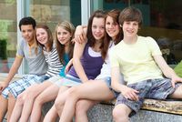 Vier Mädchen und zwei Jungen auf einer Sitzmauer