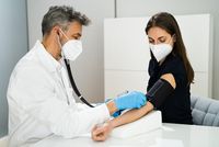 Arzt misst Blutdruck bei einer schwangeren Patientin