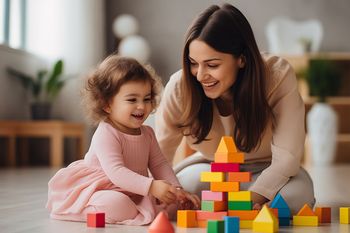 Mutter und Baby spielen vergn&uuml;gt mit bunten Baukl&ouml;tzen