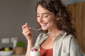 Junge frau isst Joghurt mit frischen Beeren